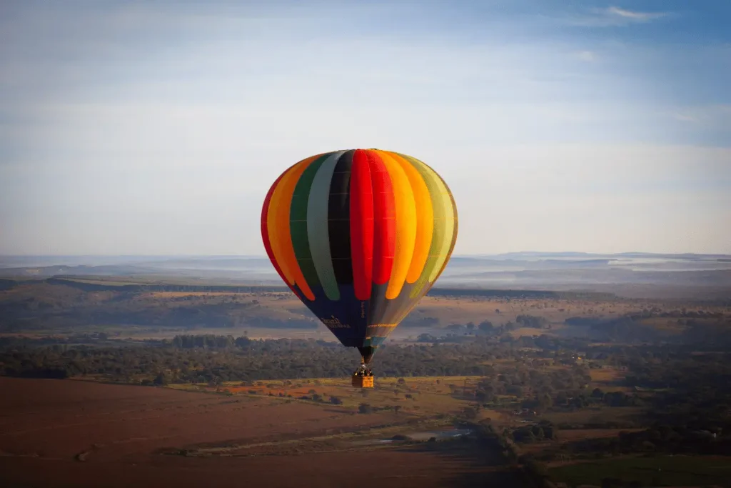 Hot air balloon flying over the plains near Marrakech at sunrise with the Atlas Mountains in the distance