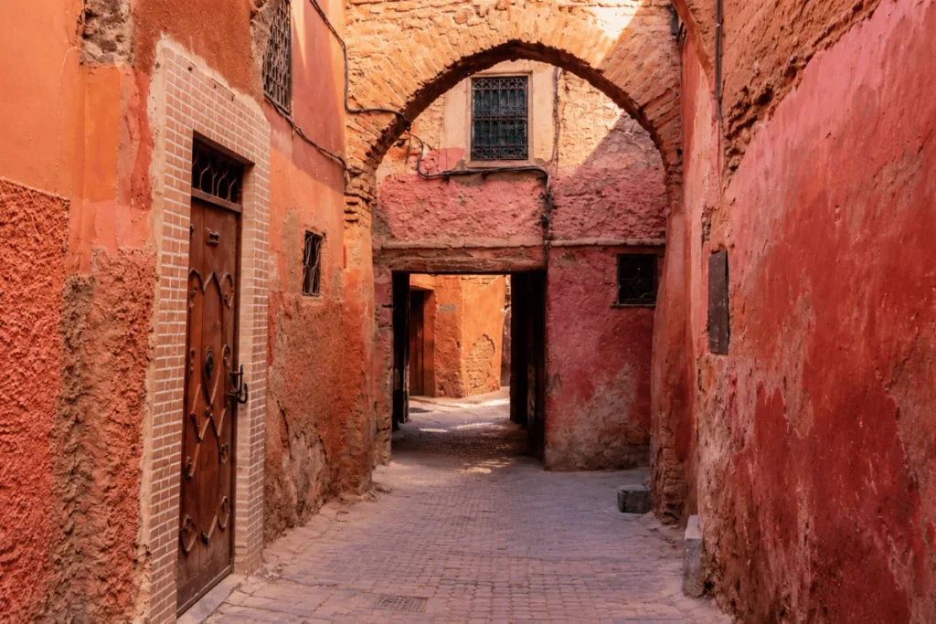 Narrow lane in Marrakech's medina leading to a traditional riad entrance.